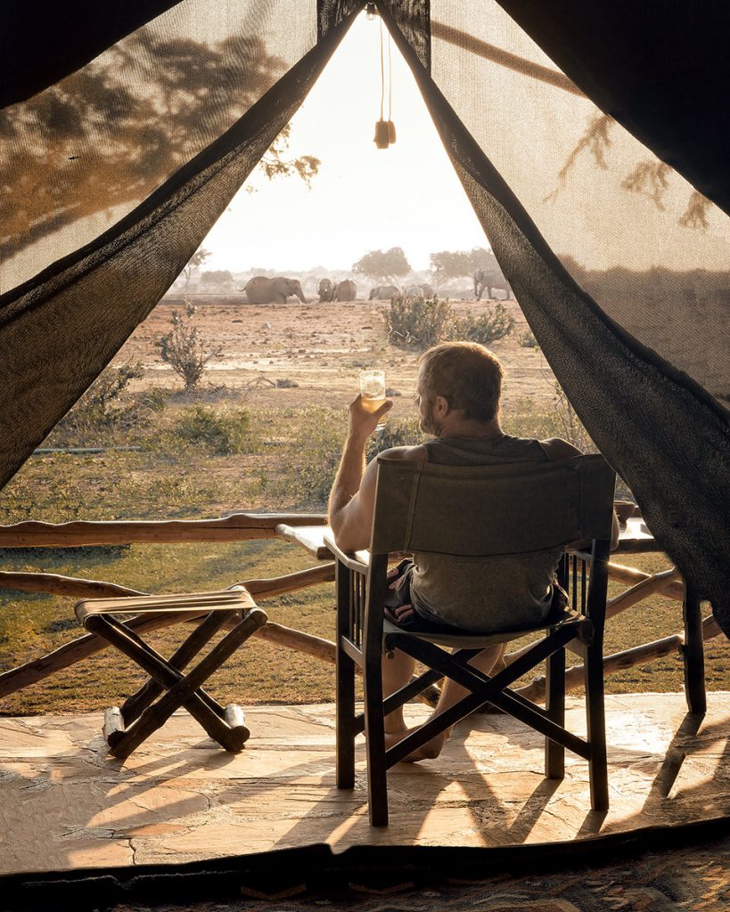 Safari guest seated inside a tent overlooking the savanna