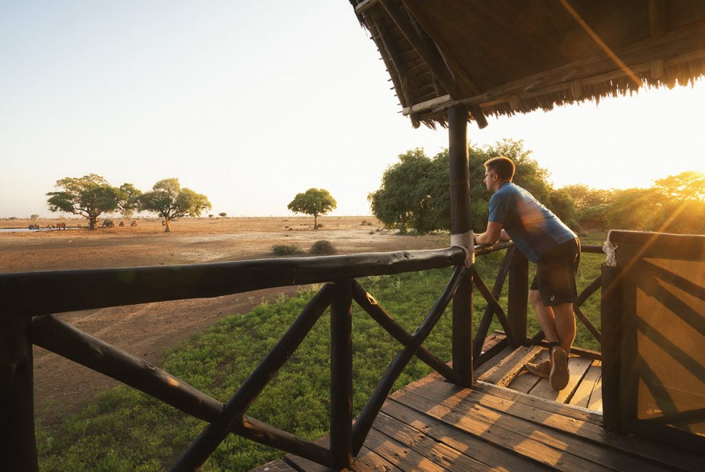 Traveler watching sunset from a safari lodge balcony