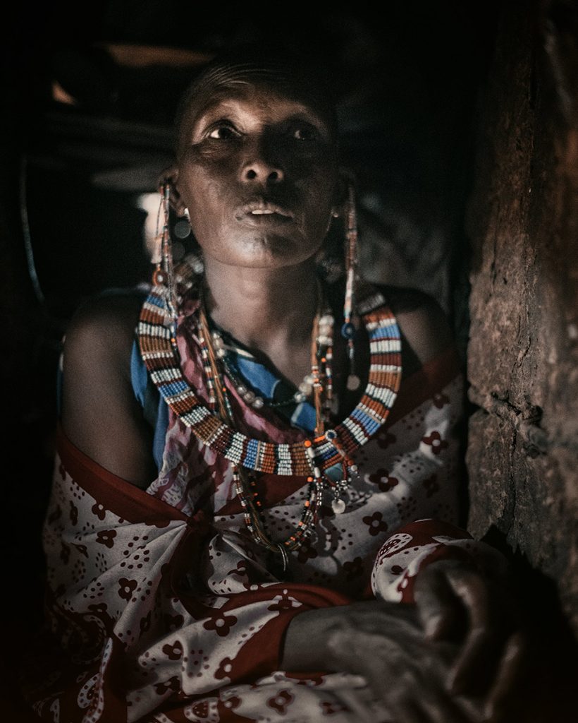 Woman wearing traditional beadwork inside a dimly lit home