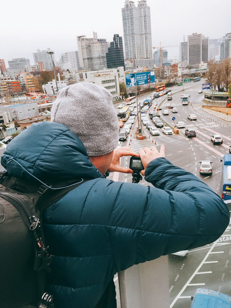 Photographer capturing city traffic from a Seoul rooftop