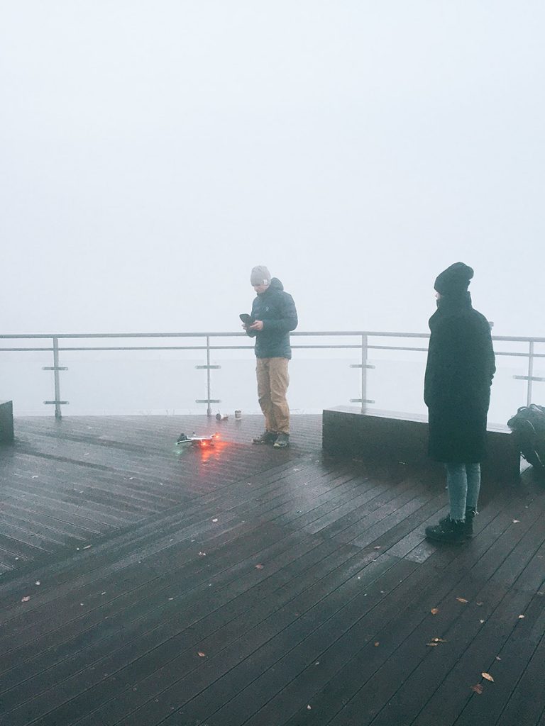 Foggy rooftop film setup with three crew members