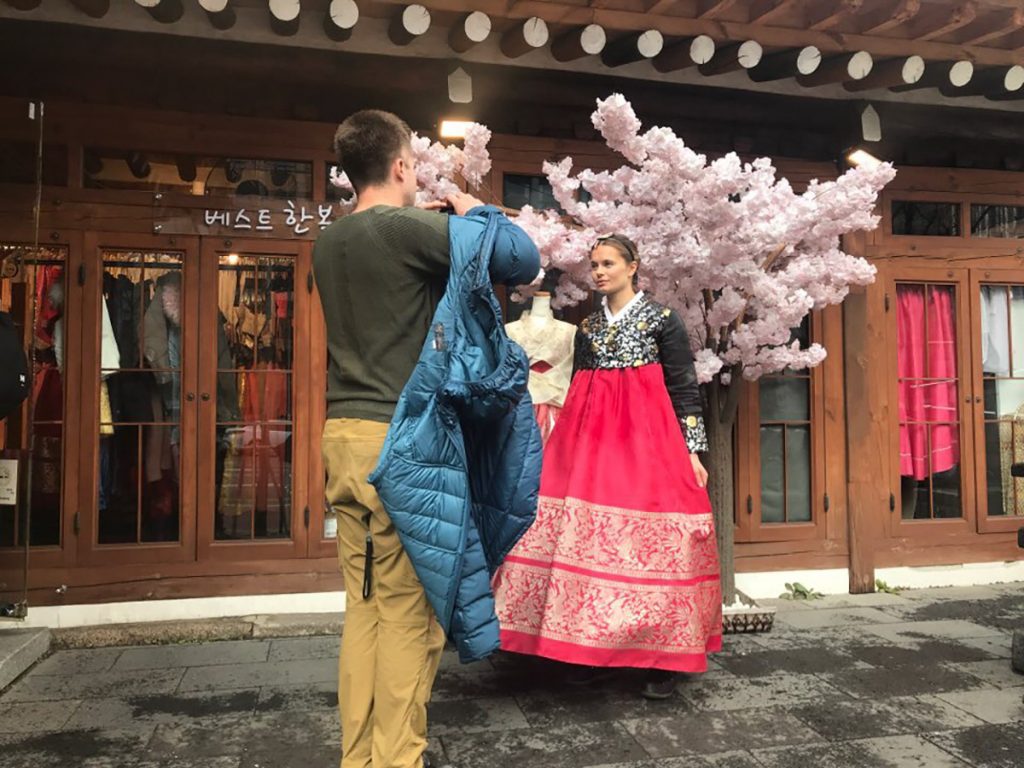 Crew filming a woman in hanbok beside cherry blossoms