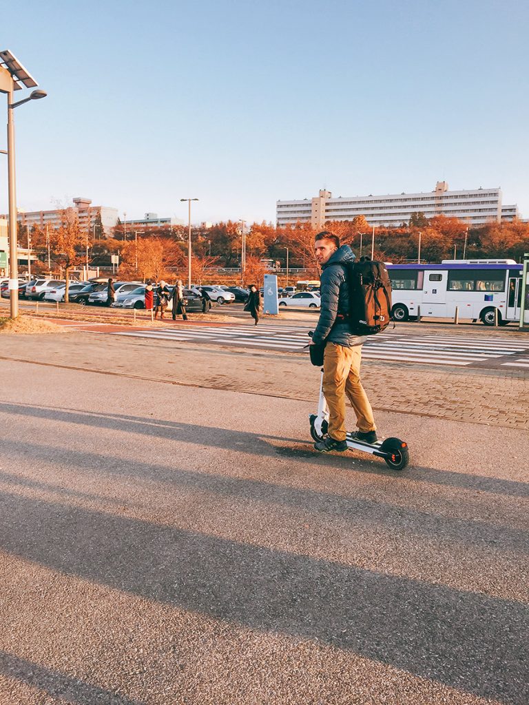Camera operator riding an electric scooter through a city square