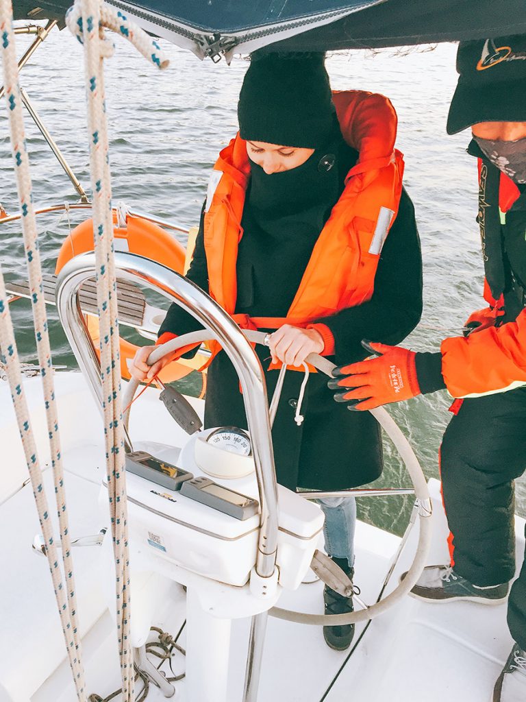 Film crew preparing a traveler at the wheel of a sailing boat