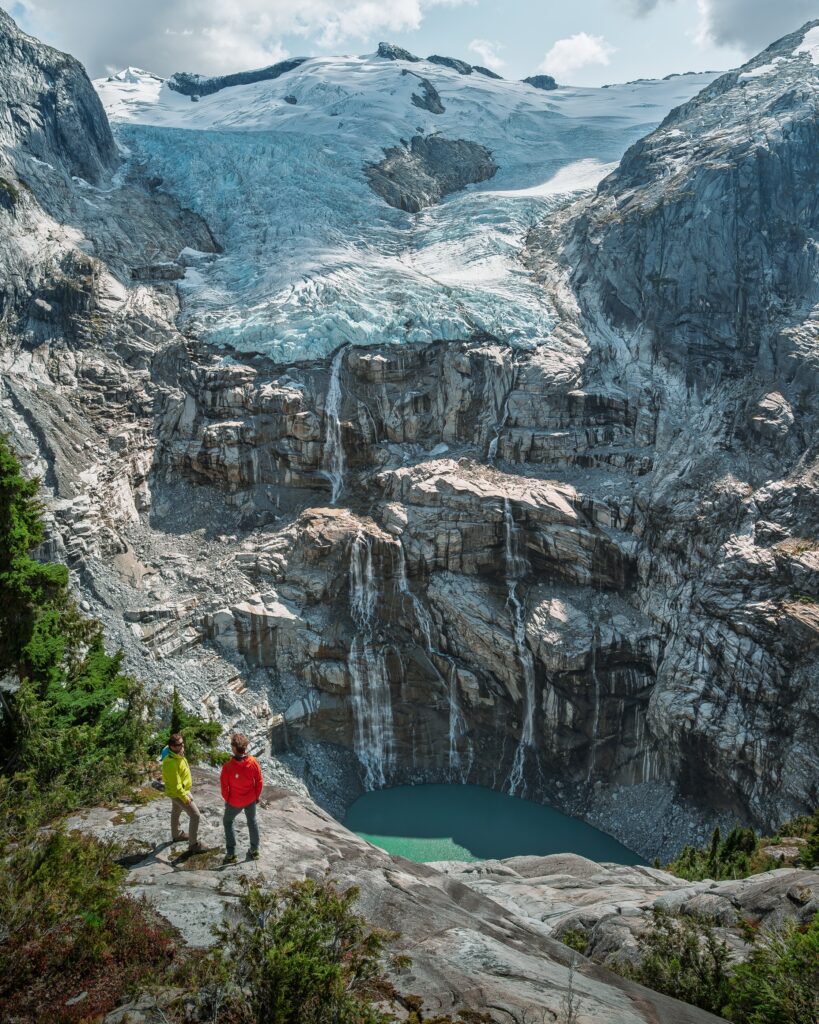 Two guests overlooking a glacier and turquoise meltwater after a helicopter flight