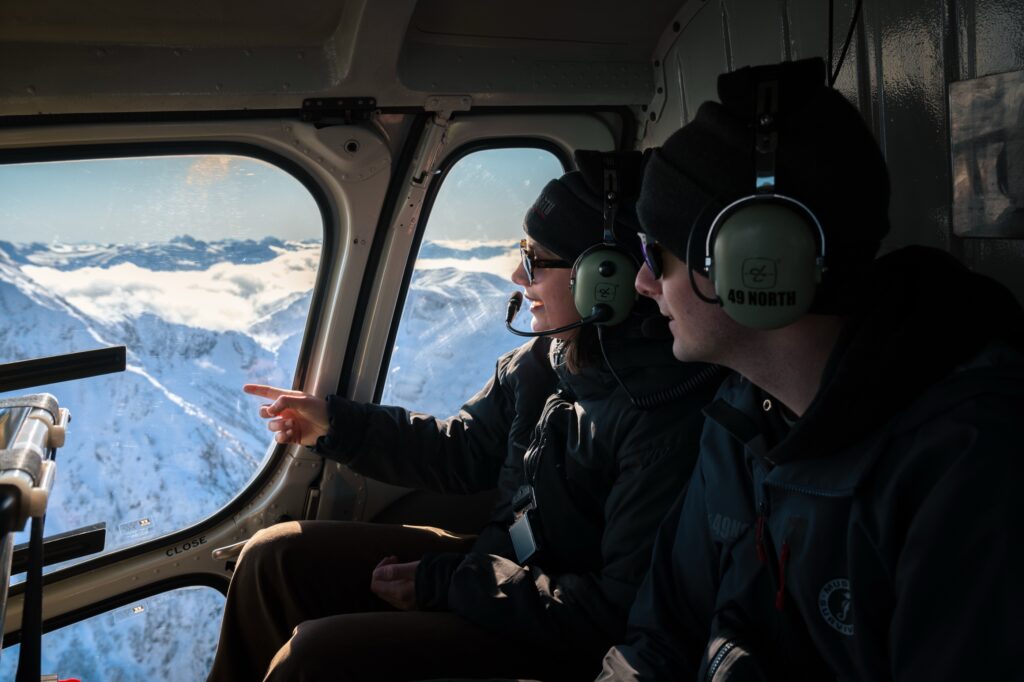 Passengers viewing snow-covered mountains from inside the helicopter