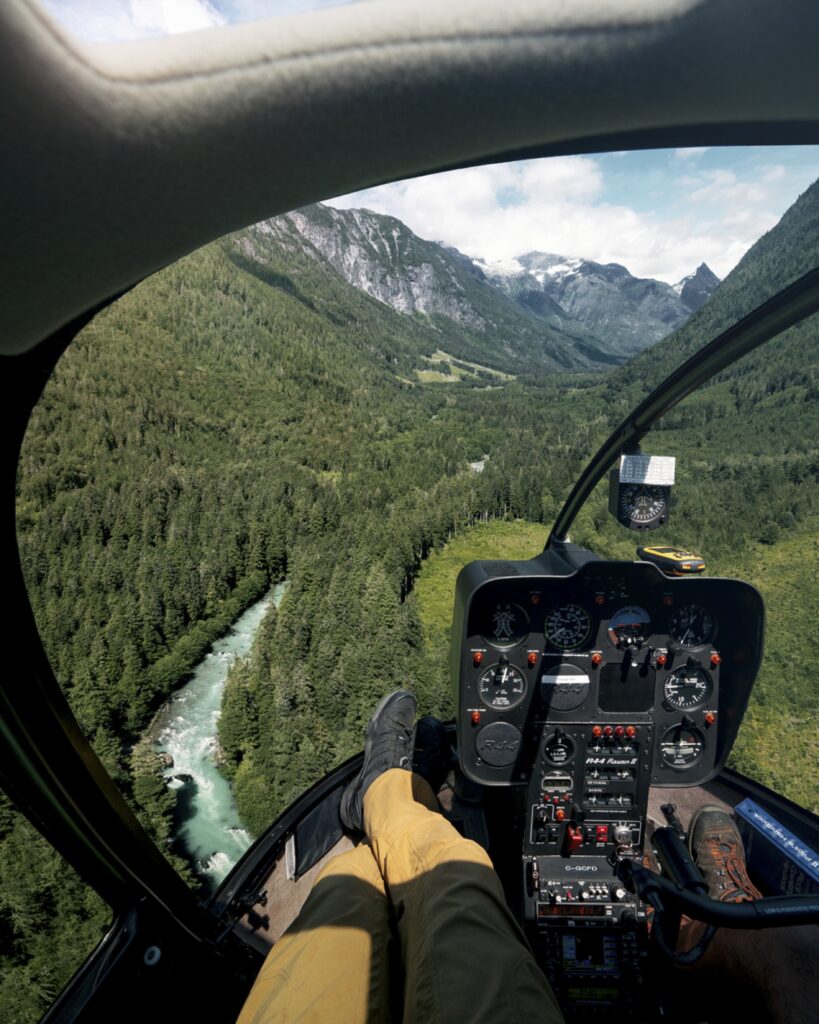 Cockpit view of a helicopter following a forested river valley