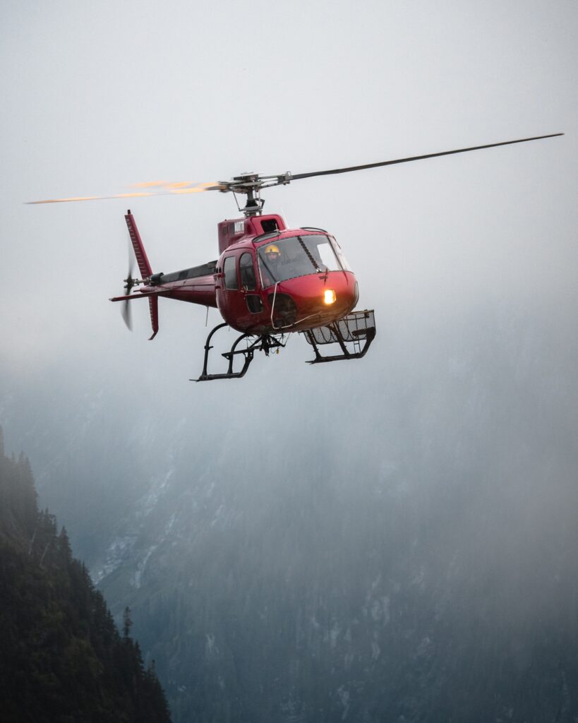 Red helicopter flying through mountain mist