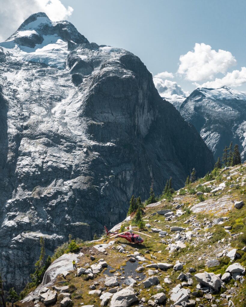 Helicopter landed beneath steep alpine peaks