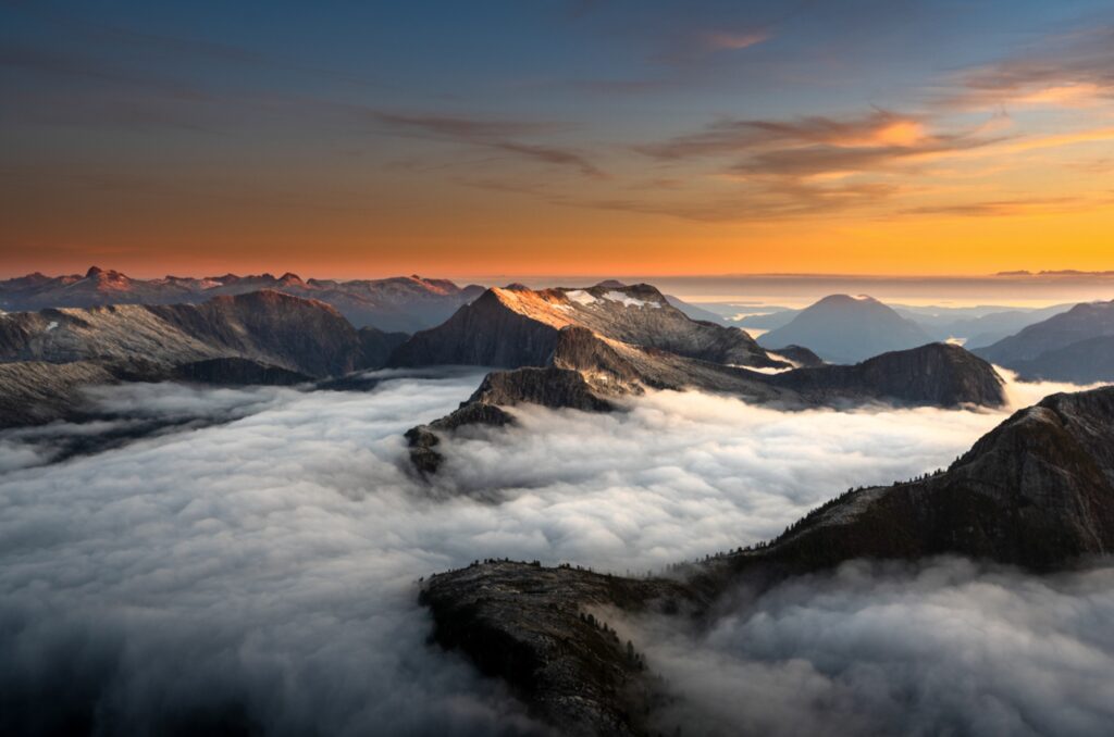 Sunset light across mountain ridges above the clouds