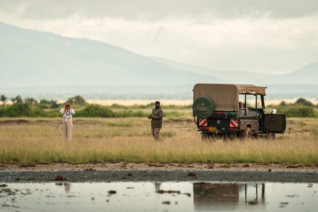 Safari vehicle and guests reflected beside a Kenyan waterhole