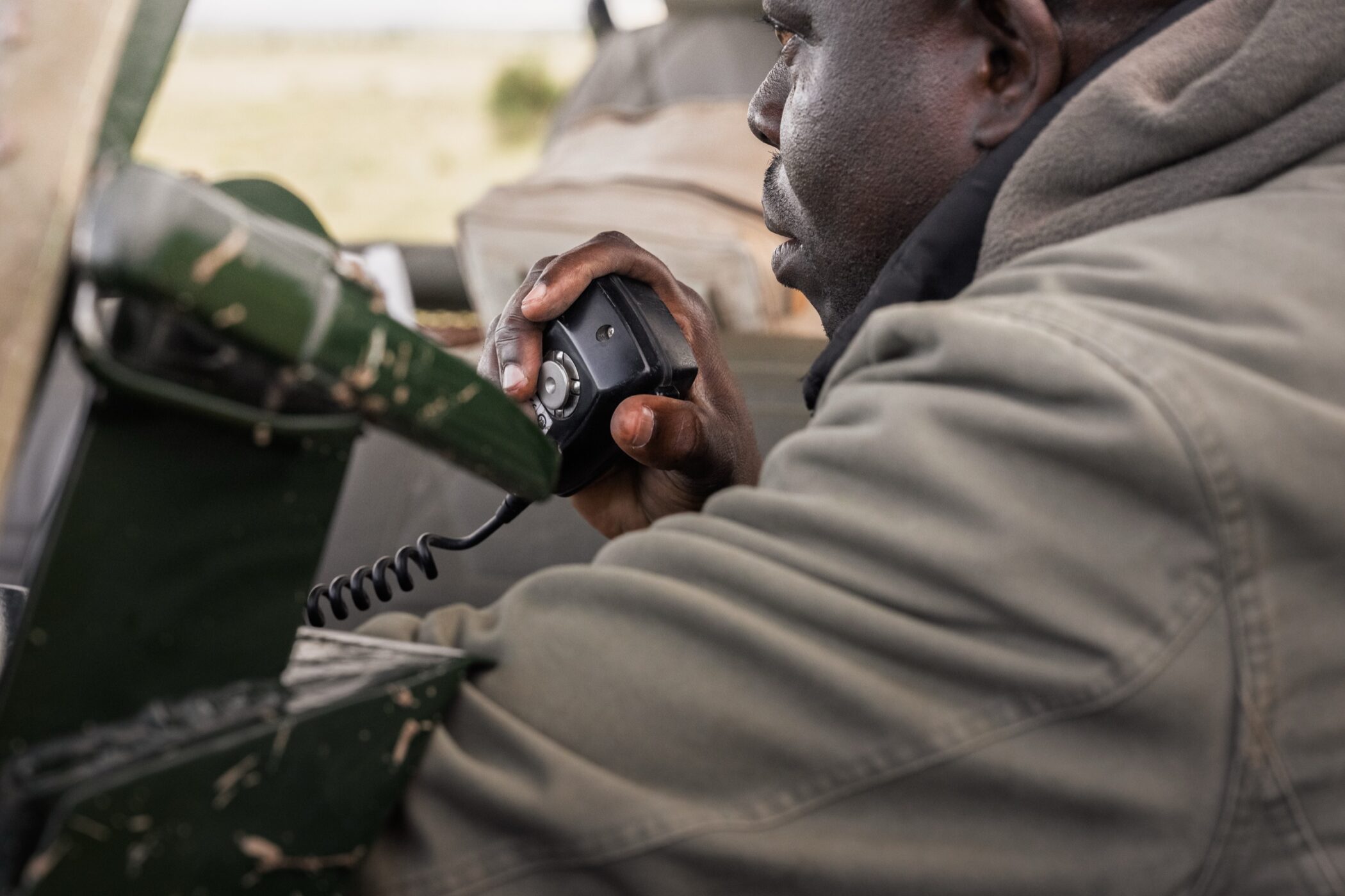 Safari guide speaking into a radio during a drive in Kenya