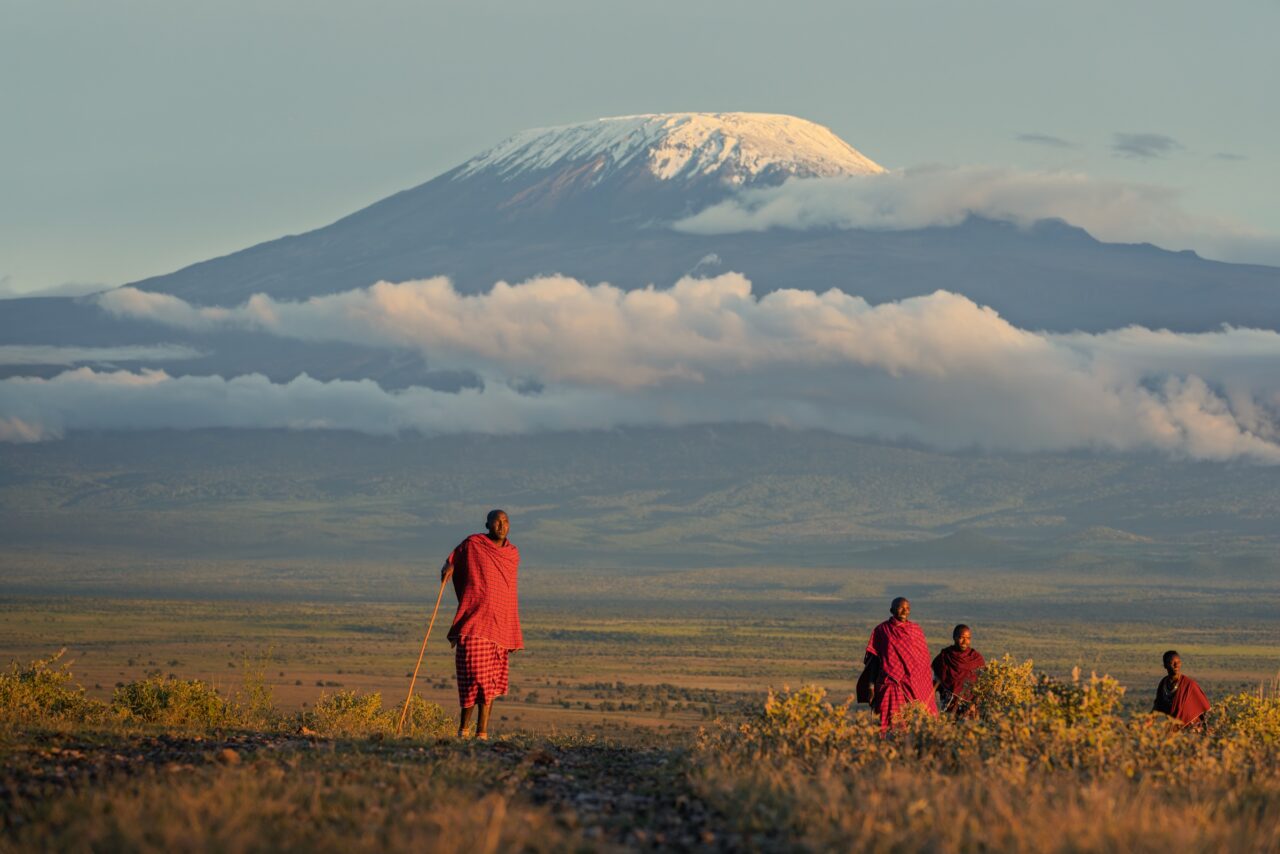 Maasai figures crossing the savanna beneath Mount Kilimanjaro