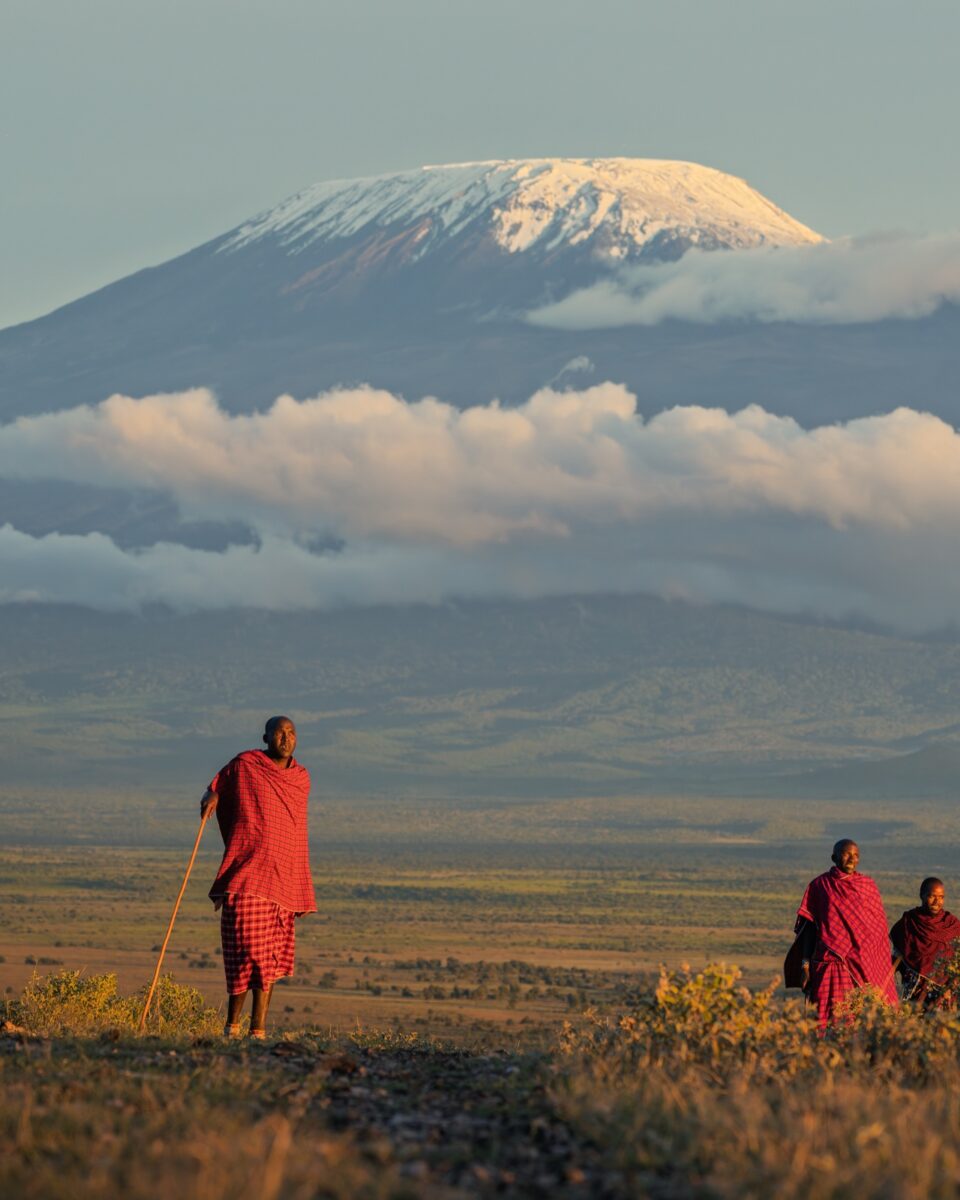 Maasai figures crossing the savanna beneath Mount Kilimanjaro