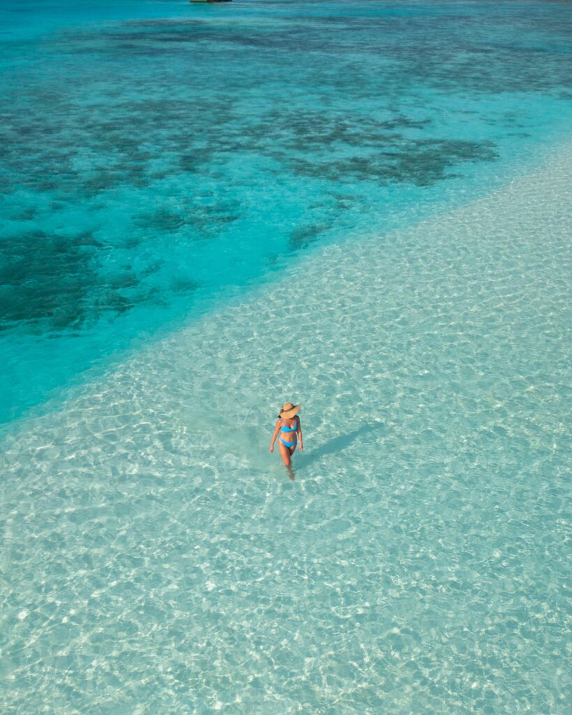 Guest paddleboarding through shallow turquoise water in the Maldives