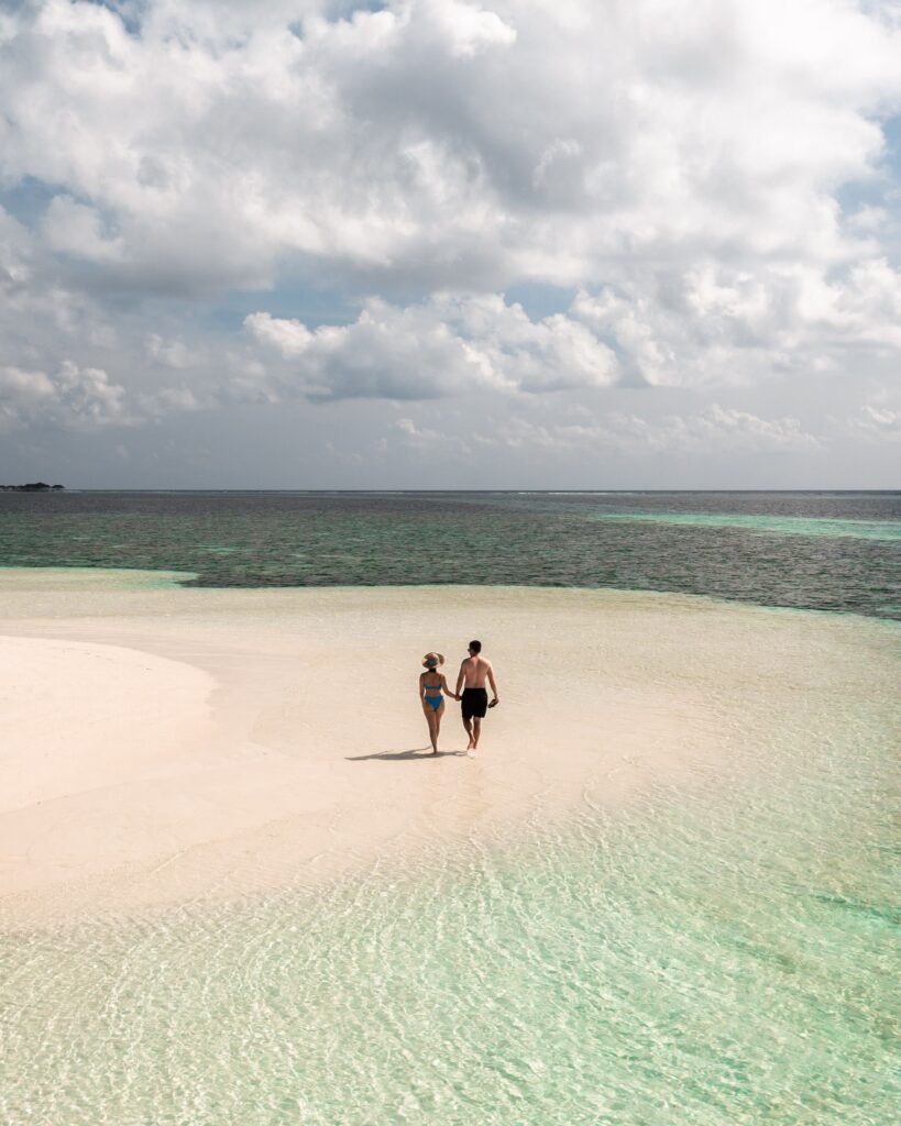 Couple walking across a white sandbank in the Maldives
