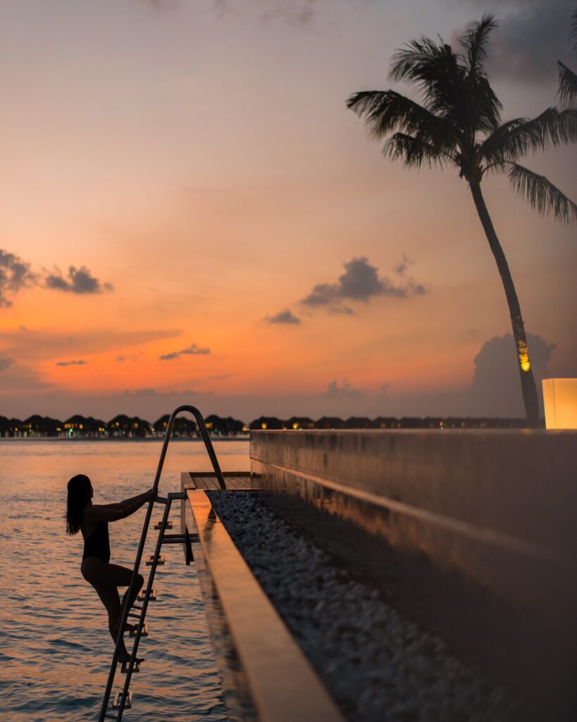 Guest entering the lagoon beside overwater villas at sunset