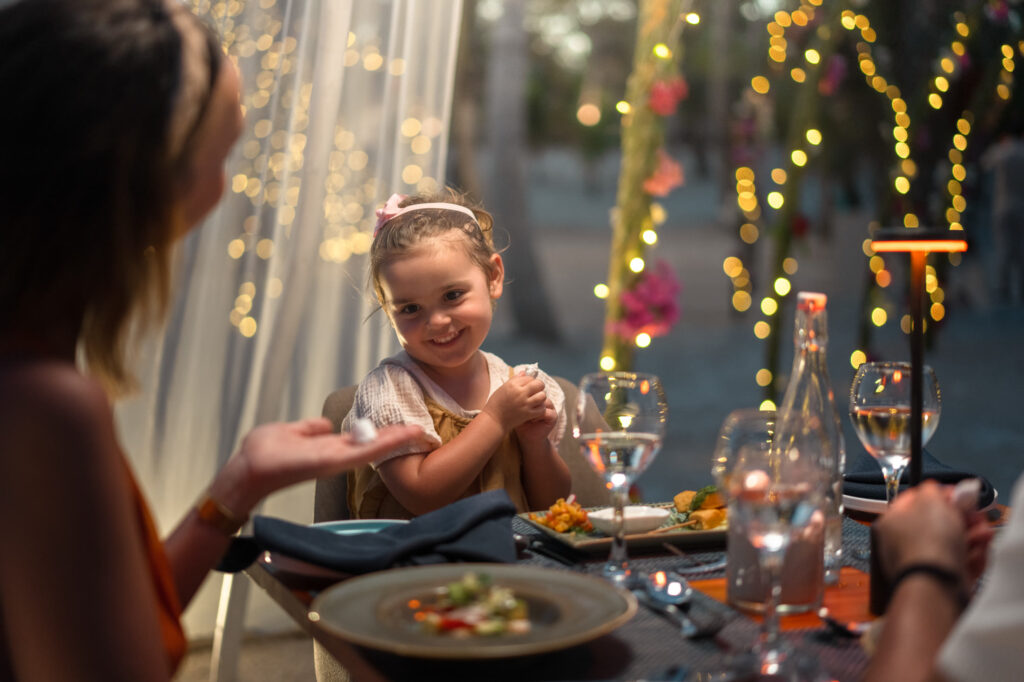 Family beach dinner illuminated by evening lights at The Mora Zanzibar