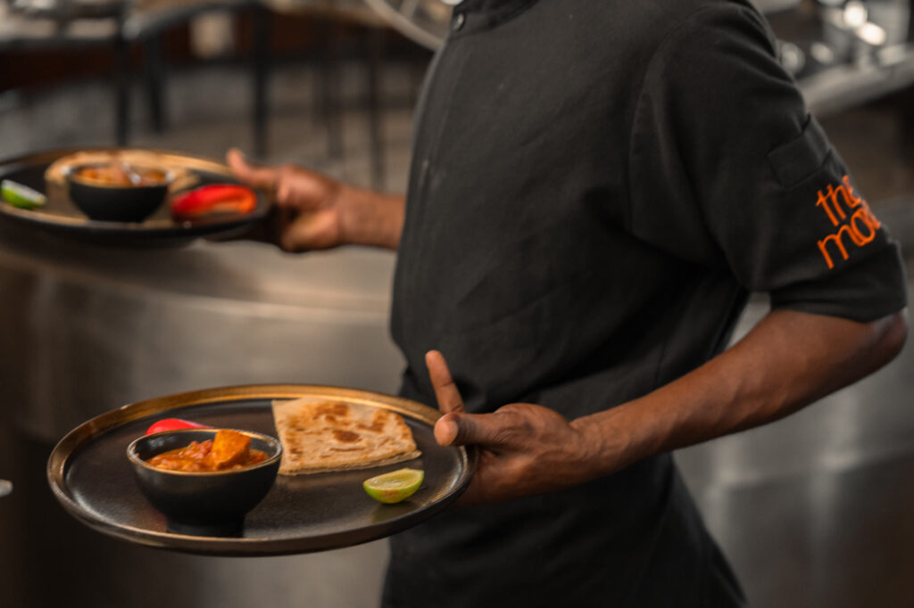 The Mora team serving a Swahili dish during a cooking experience