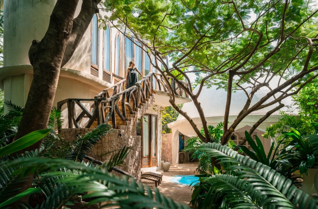 Guest on a shaded villa stairway surrounded by tropical greenery